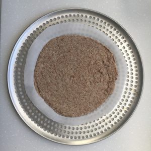 Rolled out cauliflower dough on parchment paper on a pizza tray