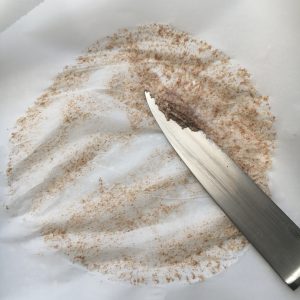 Scraping dough which is stuck to the parchment paper with the back of a knife
