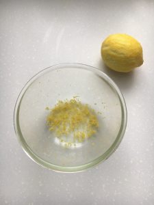 Lemon sitting by a bowl with the rind ground into it