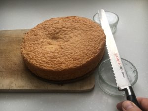 Cake being sliced horizontally with a long knife